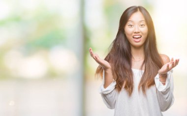 Genç Asyalı kadın deli kutluyor ve silah ile başarı için heyecanlı çığlık kaldırdı ve açık gözleri hayret izole arka plan üzerinde. Kazanan kavramı