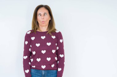 İzole arka plan yapma balık yüzüne dudaklı, çılgın ve komik bir jest kalp kazak giyen güzel orta yaş kadın. Komik ifade.