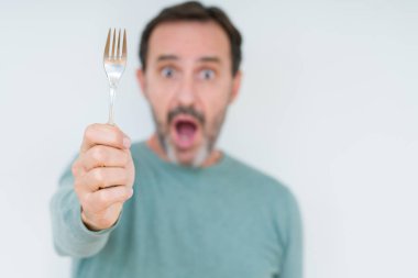 Komuta sizde gümüş çatal izole arka plan üzerinde bir sürpriz yüz, korkuyor ve heyecanlı korku ifadesi ile şok korkmuş holding