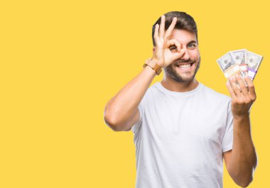 Mutlu yüz el parmaklarının arasından seyir göz üzerinde ok işaretiyle yapıyor gülümseyen izole arka plan üzerinde dolar yığını tutan genç yakışıklı adam