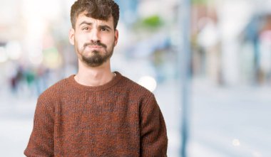 Komik surat ile yanakları şişirme izole arka plan üzerinde kış kazak giyen genç yakışıklı adam. Ağız ile hava, deli ifade şişirilmiş.