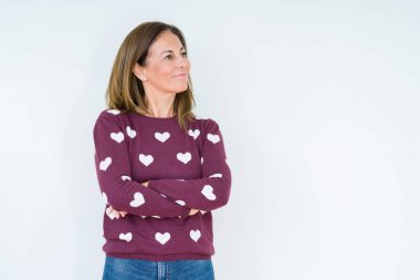 İkna ve kendine güvenen tarafına silahlarla seyir gülümseyen izole arka plan üzerinde kalp kazak giyen güzel orta yaş kadın geçti