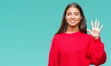 Genç güzel Arap kadın giyiyor kış kazak gösterilen ve parmakları ile işaret izole arka plan üzerinde beş kendinden emin ve mutlu gülümseyerek iken numara.