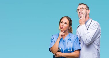 El ile izole arka plan üzerinde tıbbi üniforma giyen orta yaş İspanyol doktorlar ortakları kaç soru, dalgın ifade düşünmeye çene. Düşünceli yüzüyle gülümsüyor. Şüphe kavramı.