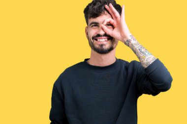 Genç yakışıklı adam gülümsüyor, parmakları ile mutlu yüz üzerinden seyir göz el ile ok jest yapıyor izole arka plan üzerinde.