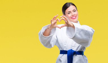 Kalp simgesi ve elleriyle şekil gösterilen aşık gülümseyen izole arka plan üzerinde karate kimono üniforma giyen genç güzel kadın. Romantik kavramı.