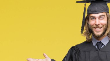 Genç yakışıklı adam uzun saçlı üzerinden hayran ve el ile sunulması ve parmak ile işaret ederken kameraya gülümseyen izole arka plan mezun oldu.