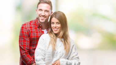 Genç çift aşık yüzünde mutlu ve güzel bir gülümseme ile izole arka plan üzerinde kış kazak giyiyor. Şanslı kişi.