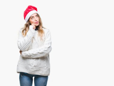 Çene düşünme hakkında soru, dalgın ifade üzerine el ile izole arka plan üzerinde Noel şapka giyen güzel genç sarışın kadın. Düşünceli yüzüyle gülümsüyor. Şüphe kavramı.