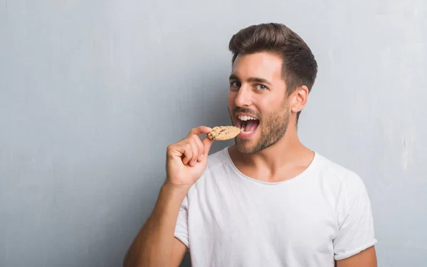 Guapo Joven Sobre Gris Grunge Pared Comer Chocolate Chip Cooky — Foto de Stock