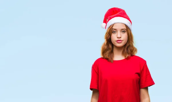 若い美しい女性の顔に真剣な表情でクリスマス帽子をかぶっている孤立した背景の上 シンプルで自然なカメラを見てください — ストック写真