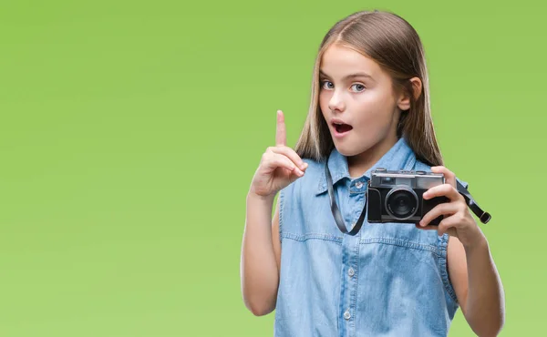 年轻美丽的女孩拍摄照片使用复古相机在孤立的背景惊讶与一个想法或问题指向手指与快乐的脸 — 图库照片