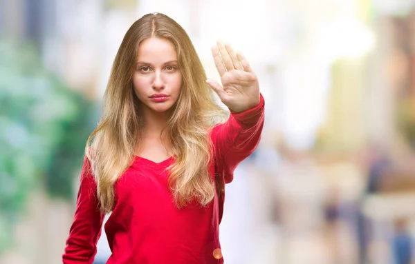 停止を行う分離の背景に赤いセーターを着ている若い美しいブロンドの女性は 手のひらの上で歌います 顔に否定的な深刻なジェスチャーで警告式 — ストック写真