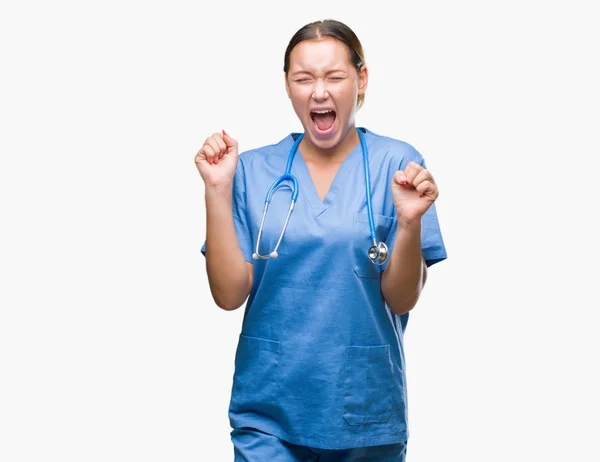 孤立した背景を祝う上医療制服を着て若い白人医師女性驚いて腕を上げると成功のため驚くし 目を開きます 勝者の概念 — ストック写真