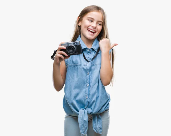 年轻美丽的女孩拍照使用老式相机在孤立的背景指向和显示与快乐的脸微笑的一侧与拇指 — 图库照片