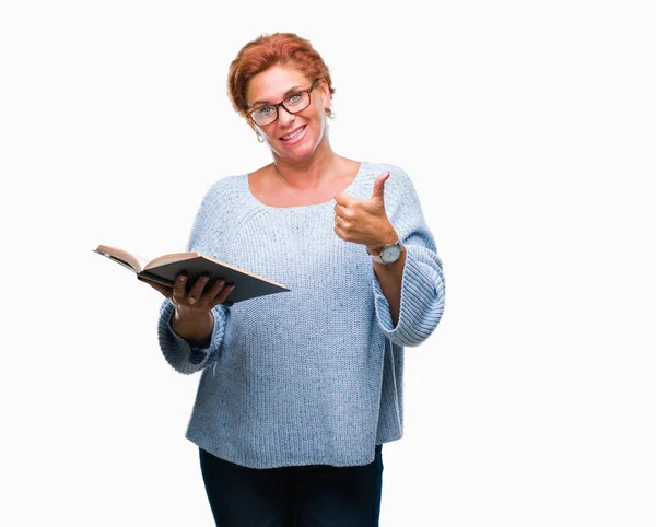 高级白种人妇女读一本书在孤立的背景高兴与灿烂的微笑做确定的标志 用手指竖起大拇指 优秀的标志 — 图库照片
