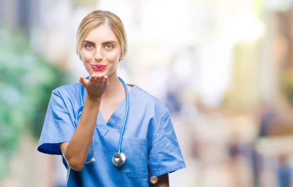 若い美しい金髪の医者の外科医看護師女性オンエアされて素敵なセクシーな手でキスを吹いてカメラ目線孤立の背景の上 愛情表現 — ストック写真