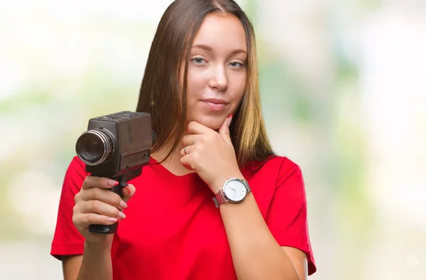 若い美しい白人女性に関する質問は 非常に混乱して考え分離背景深刻な顔を考えての上ヴィンテージ ビデオ カメラを使用して撮影 — ストック写真