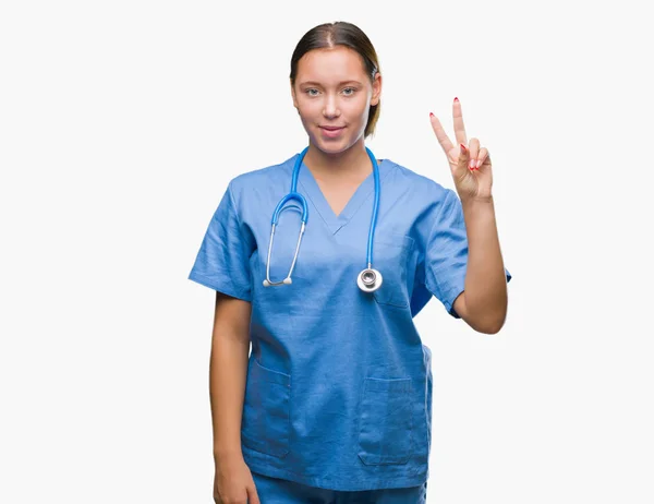 上医療制服を着て若い白人医師女性分離を示す背景と自信を持って 幸せな笑みを浮かべている間 つ番号を指で上向き — ストック写真