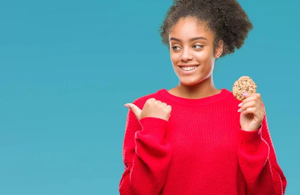 Junge Afroamerikanerin Isst Schokoladenkeks Über Isoliertem Hintergrund Und Zeigt Mit — Stockfoto