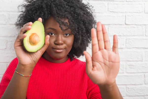 Joven Mujer Afroamericana Sobre Pared Ladrillo Blanco Comiendo Aguacate Con —  Fotos de Stock