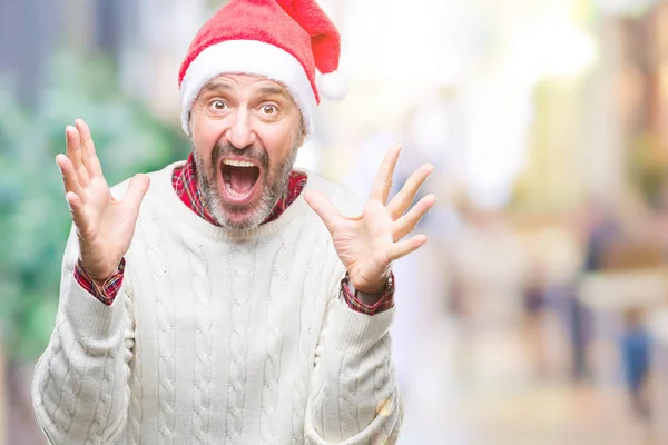 中年老人戴着圣诞节帽在孤立的背景下庆祝疯狂和惊讶的成功与双臂举起和睁开的眼睛尖叫兴奋 获奖者概念 — 图库照片