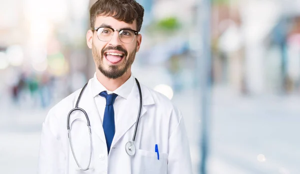 Junger Arzt Krankenhausmantel Über Isoliertem Hintergrund Streckt Die Zunge Glücklich — Stockfoto