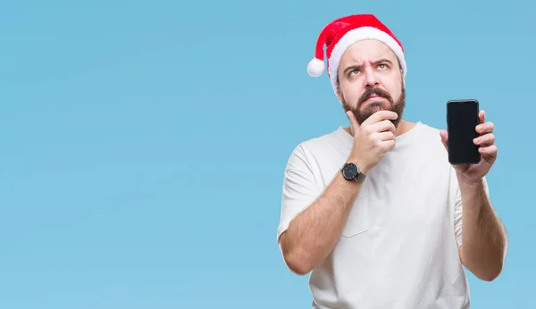 非常に混乱しているアイデアについて分離背景深刻な顔を考えての上クリスマス帽子 表示中のスマート フォンの画面を着た若い白人男 — ストック写真