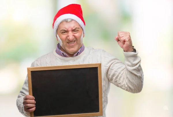 英俊的老人戴着圣诞帽子 并持有黑板在孤立的背景恼火和沮丧的叫喊与愤怒 疯狂和吆喝举手 愤怒的概念 — 图库照片