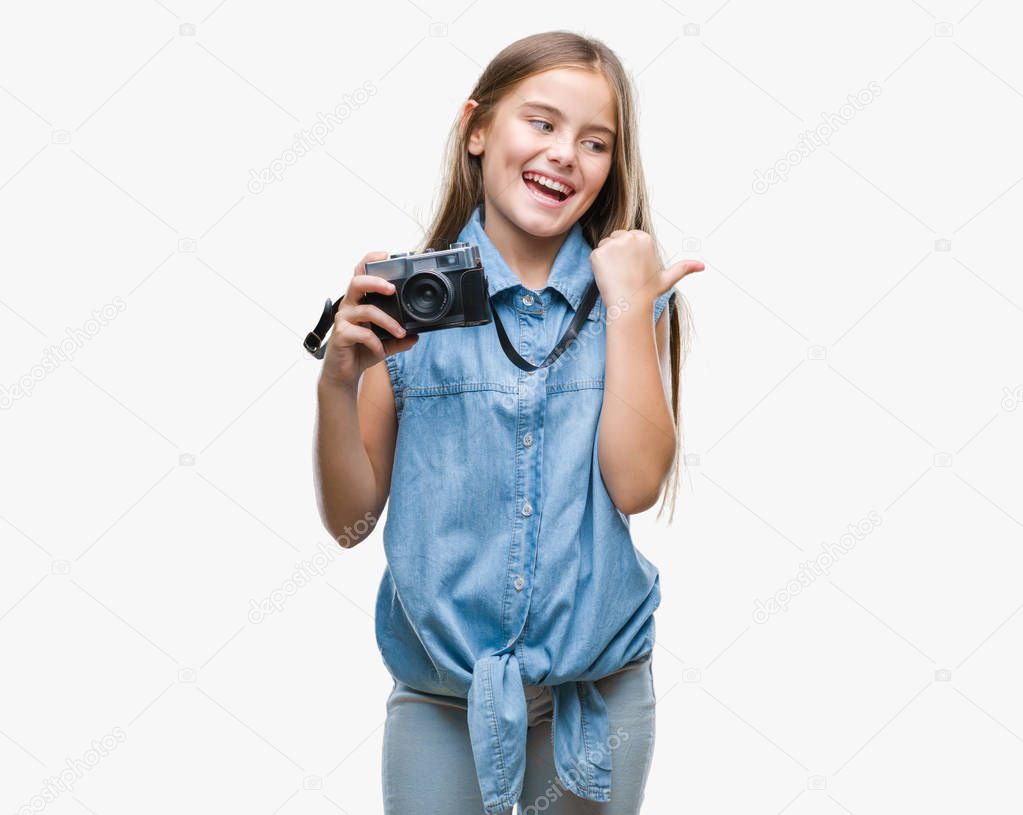 Young beautiful girl taking photos using vintage camera over isolated background pointing and showing with thumb up to the side with happy face smiling