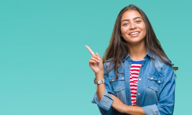 Yüzünde kocaman bir gülümseme ile izole arka plan üzerinde genç güzel Arap kadın kameraya bakarak yan el ve parmak ile işaret.