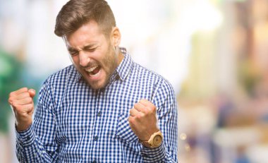 Soyutlanmış, mutlu ve heyecanlı genç bir adam kollarını kaldırmış, gülümseyen ve başarı için çığlık atan kazanan bir jest yapıyor. Kutlama konsepti.