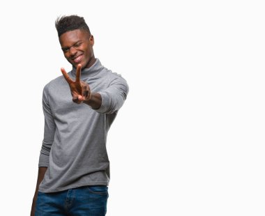 Afrikalı-Amerikalı genç zafer işareti yapıyor parmak gösterilen kamera seyir gülümseyen izole arka plan üzerinde. İki numaralı.