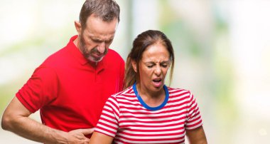 Orta yaş İspanyol çift aşık ile izole arka plan üzerinde elini karnına çünkü hazımsızlık, ağrılı hastalık hasta hissediyor. Ağrısı kavramı.