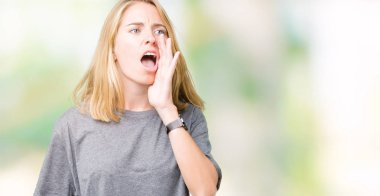 Bağırarak ve ağzı üzerinde el ile yan için çığlık izole arka plan üzerinde büyük boy rahat t-shirt giyen güzel ve genç birbayan. İletişim kavramı.