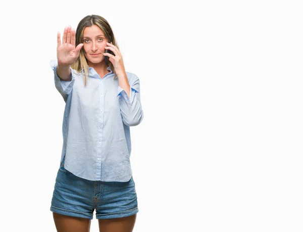 年轻的美女在智能手机上交谈在孤立的背景与开放的手做停止标志与严肃和自信的表达 防御姿态 — 图库照片