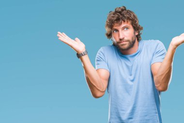 Yakışıklı İspanyol modeli adam izole arka plan clueless ve şaşkın bir ifadeyle kollar ve eller kaldırdı. Şüphe kavramı.