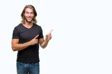 Gülümseyen ve iki elleri ve parmakları ile tarafına işaret kamera bakarak izole arka plan üzerinde uzun saçlı yakışıklı delikanlı.