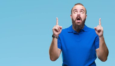 Giyiyor mavi gömlek izole arka plan üzerinden hayran ve yukarıya bakıp parmakları ile işaret şaşırttı ve silah kaldırdı Genç beyaz hipster adam.