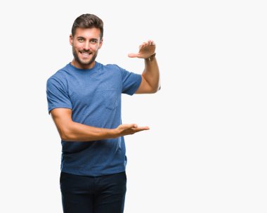 Yakışıklı delikanlı ile büyük ve büyük boy işaret, ölçü birimi sembol gösteren el eller izole arka plan üzerinde. Kameraya bakarak gülümsüyordu. Ölçüm kavramı.