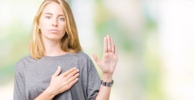 Güzel genç kadın üzerinde büyük boy rahat t-shirt giyen izole arka plan göğüs ve bir sadakat sözü yemin yapma avuç, el ile küfür