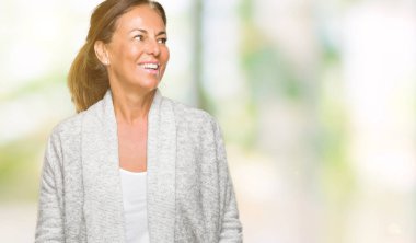 Üzerinde kış kazak giyen güzel orta yaş yetişkin kadın arka plan uzak tarafına gülümseme ile yüzünde, doğal ifade arıyorum izole. Kendine güvenen gülüyor.