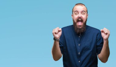 İzole arka plan kutlama üzerinde genç beyaz hipster adam şaşırttı ve başarı için kaldırdı kollarını açarak hayret ve gözleri açık. Kazanan kavramı.