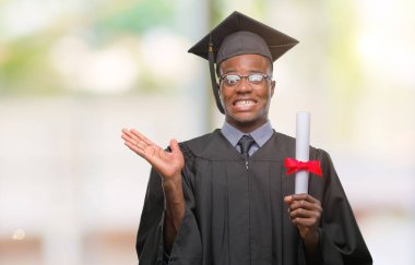 Genç Afro-Amerikan adam derecesi izole arka plan üzerinde çok mutlu ve heyecanlı, kocaman bir gülümseme ile çığlık ve ellerini kaldırdı kazanan ifade kutluyor zafer tutarak mezun oldu.