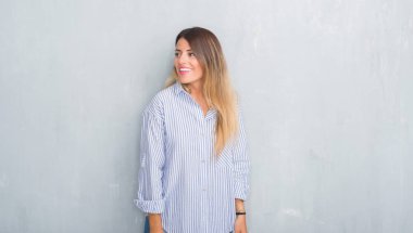 Genç Yetişkin kadın moda iş kıyafeti uzak tarafına gülümseme ile yüzünde, doğal ifade arıyorsunuz giyen gri grunge duvarın üzerinden. Kendine güvenen gülüyor.