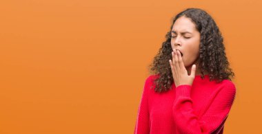 Kırmızı kazak giyen genç İspanyol kadın el ağzıyla kapsayan yorgun esneme sıkılmış. Restless ve uyku hali.