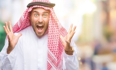 Keffiyeh üzerinde giyen genç yakışıklı adam deli kutluyor arka plan izole ve silah ile başarı için yükseltilmiş ve açık gözleri heyecanlı çığlık hayrete düşürdü. Kazanan kavramı