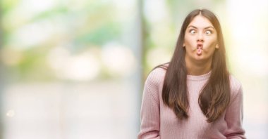 Bir kazak yapımı balık yüz dudaklı, çılgın ve komik bir jest giyen genç güzel İspanyol kadın. Komik ifade.