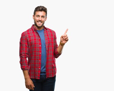 Kameraya bakarak yan el ve parmak ile işaret eden genç yakışıklı adam yüzünde kocaman bir gülümseme ile izole arka plan üzerinde.