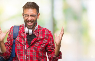 Üzerinde kulaklık ve sırt çantası giyiyor yetişkin İspanyol öğrenci adam arka plan deli kutluyor izole ve crazy arms ile başarı için kaldırdı ve heyecanlı çığlık gözler kapalı. Kazanan kavramı